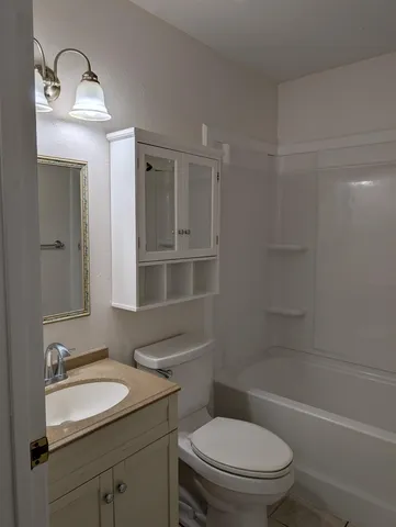 a bathroom with a sink toilet vanity granite tub and shower
