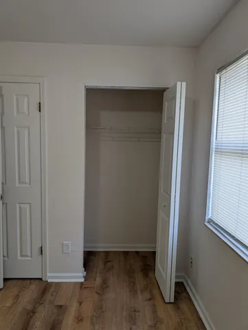 an empty room with wooden floor and closet area