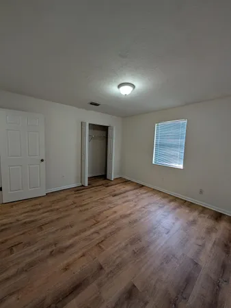 an empty room with wooden floor and windows