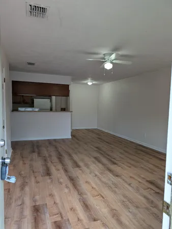 a view of empty room with wooden floor and ceiling fan