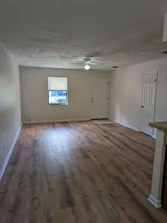 a view of an empty room with wooden floor and a window