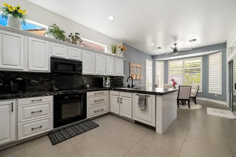 a kitchen with granite countertop white cabinets white stainless steel appliances with a dining table and chairs