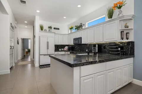a kitchen with stainless steel appliances granite countertop a refrigerator a sink and white cabinets