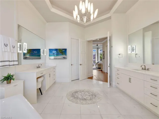 a large white kitchen with cabinets and chandelier