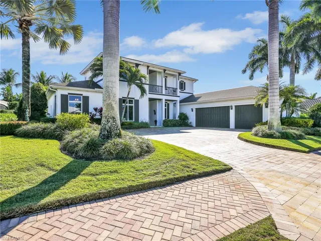 a front view of a house with a yard and palm trees