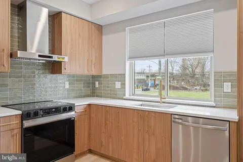 a kitchen with stainless steel appliances granite countertop a refrigerator a sink a stove and white cabinets with wooden floor