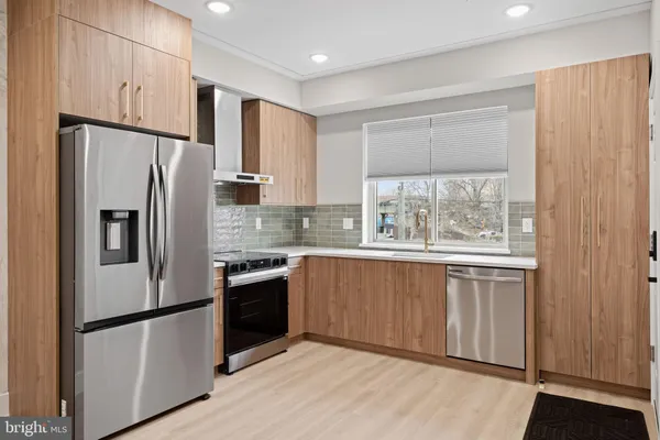 a view of an empty room with wooden floor kitchen and windows