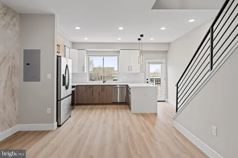 a kitchen with stainless steel appliances granite countertop a refrigerator a sink dishwasher a stove and white cabinets with wooden floor