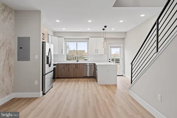 a kitchen with stainless steel appliances granite countertop a refrigerator a sink dishwasher a stove and white cabinets with wooden floor