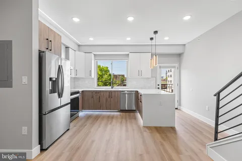 a kitchen with stainless steel appliances a refrigerator and a wooden floor