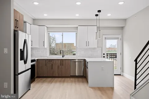 a large kitchen with a wooden floor and stainless steel appliances