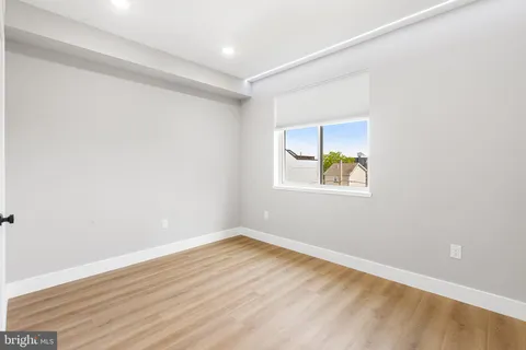 an empty room with wooden floor and window