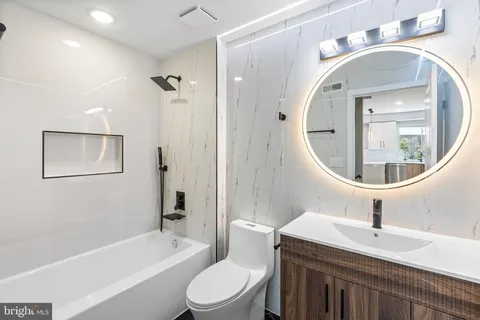 a bathroom with a toilet a sink a mirror and bathtub
