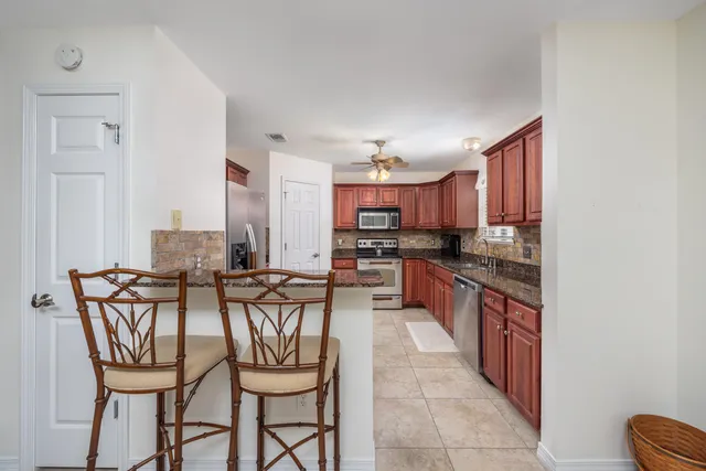 a kitchen with stainless steel appliances kitchen island granite countertop a table chairs and a refrigerator