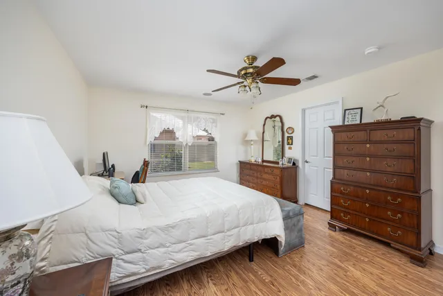a bedroom with a bed a dresser and wooden floor