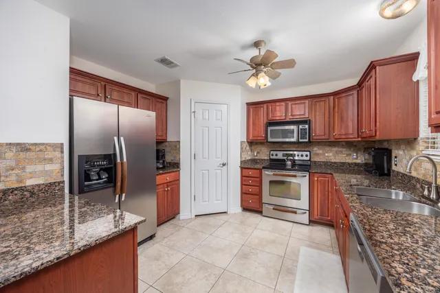 a kitchen with stainless steel appliances granite countertop a refrigerator a stove and a sink with granite countertops
