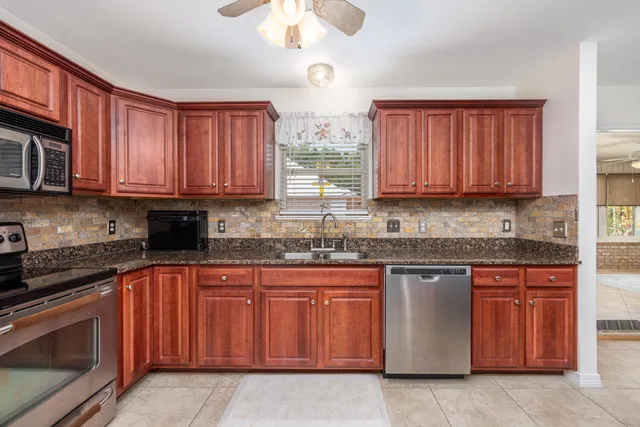 a kitchen with stainless steel appliances granite countertop wooden cabinets a stove a sink and dishwasher