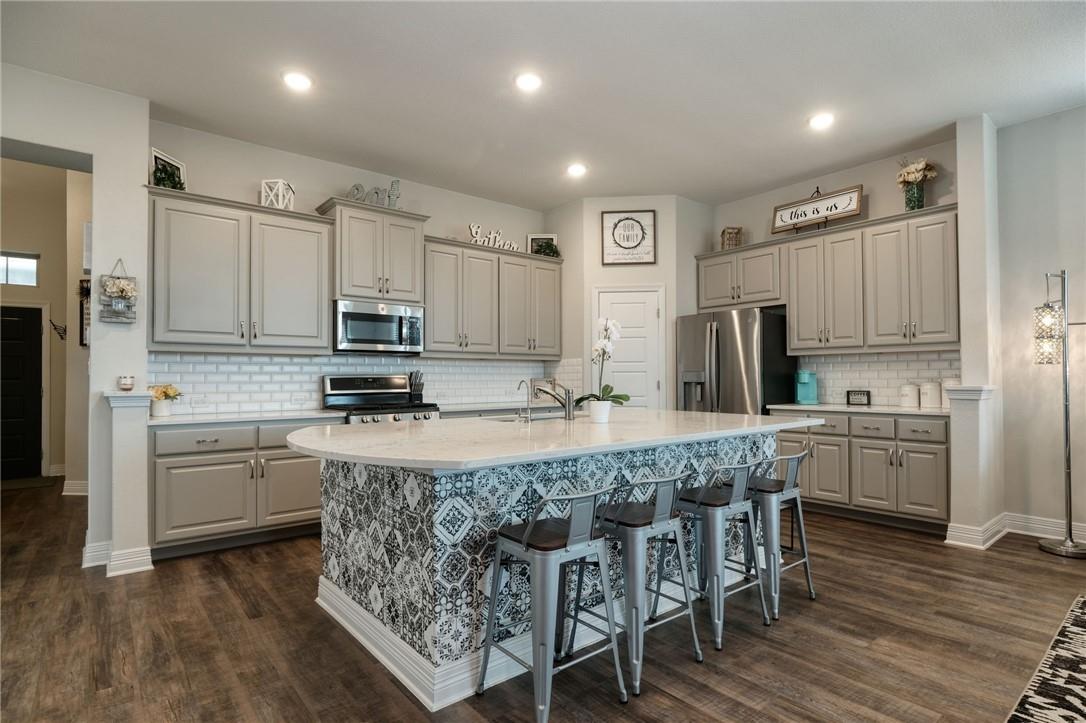 229 Bonnet Boulevard Georgetown, TX 78628 - Photo 2 of 20 a kitchen with kitchen island granite countertop a stove a sink a refrigerator cabinets and wooden floor