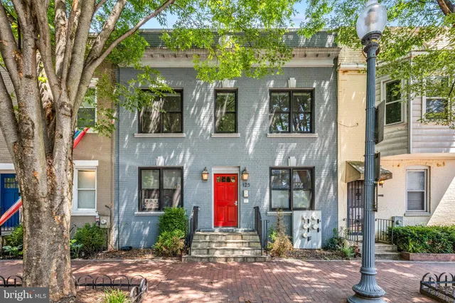 a front view of a brick house with a large windows and a large tree
