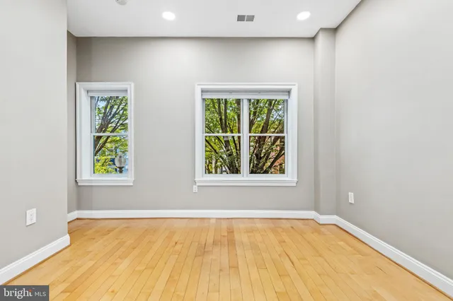 a view of an empty room with wooden floor and a window