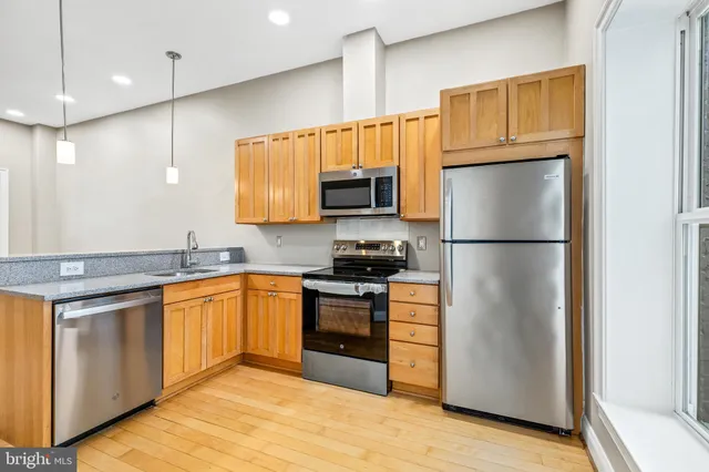 a kitchen with granite countertop a refrigerator and a stove top oven