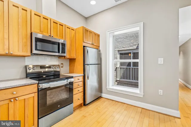 a kitchen with granite countertop wooden cabinets stainless steel appliances and a window