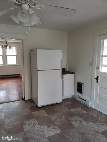 a view of a refrigerator in kitchen and an empty room