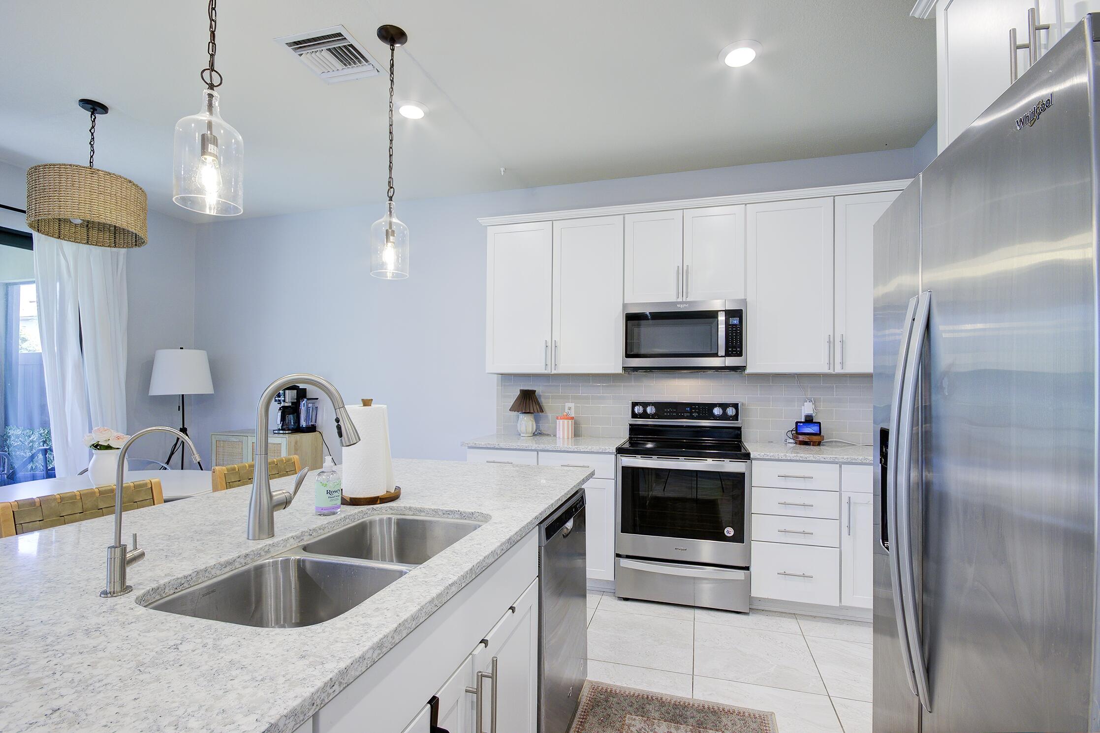 8327 Rearing Lane Lake Worth, FL 33467 - Photo 9 of 31 a kitchen with white cabinets and stainless steel appliances