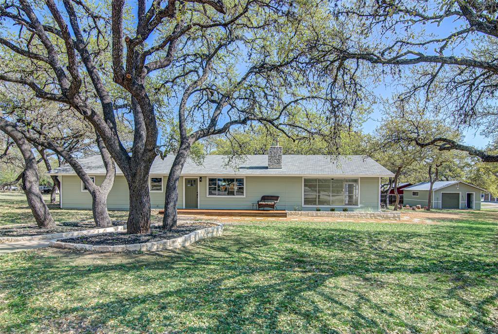 207 Haley Road Johnson City, TX 78636 - Photo 31 of 31 Mature trees frame a charming home with a welcoming front deck and detached garage.