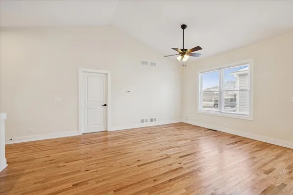 a view of empty room with wooden floor and fan