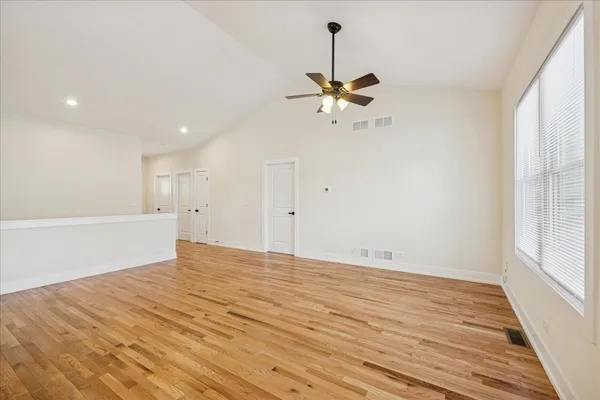 a view of empty room with wooden floor and fan