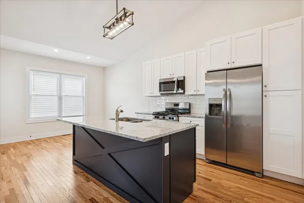 a kitchen with kitchen island granite countertop a sink appliances cabinets and wooden floor