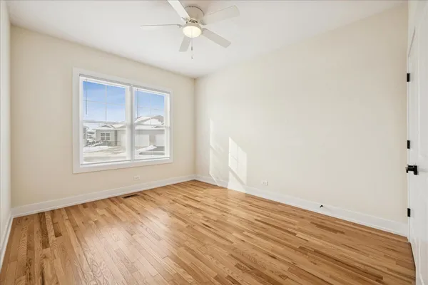 a view of empty room with wooden floor and fan
