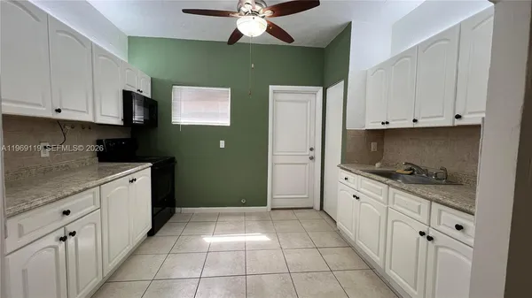 a kitchen with granite countertop a sink a stove top oven and cabinets