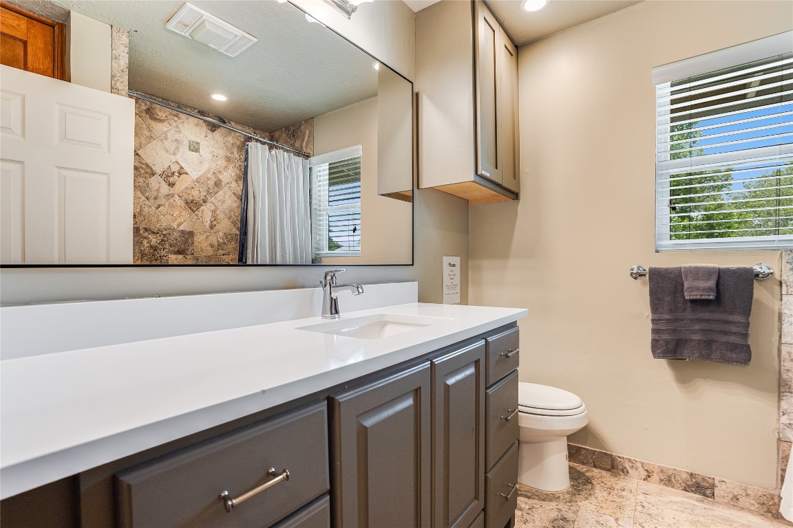 2308 Flite Acres Road Wimberley, TX 78676 - Photo 18 of 35 a bathroom with a granite countertop sink a toilet and a mirror