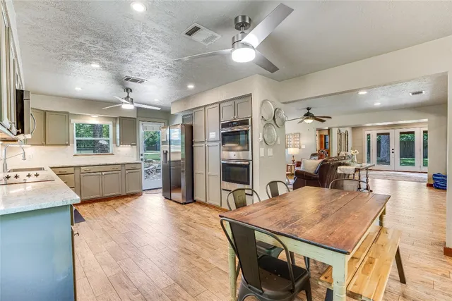 a kitchen with a stove a refrigerator a sink dishwasher a dining table and chairs with wooden floor