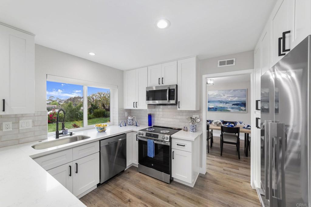 460 Compass Road Oceanside, CA 92054 - Photo 12 of 45 a kitchen with stainless steel appliances a stove a sink dishwasher a refrigerator and a dining table with wooden floor