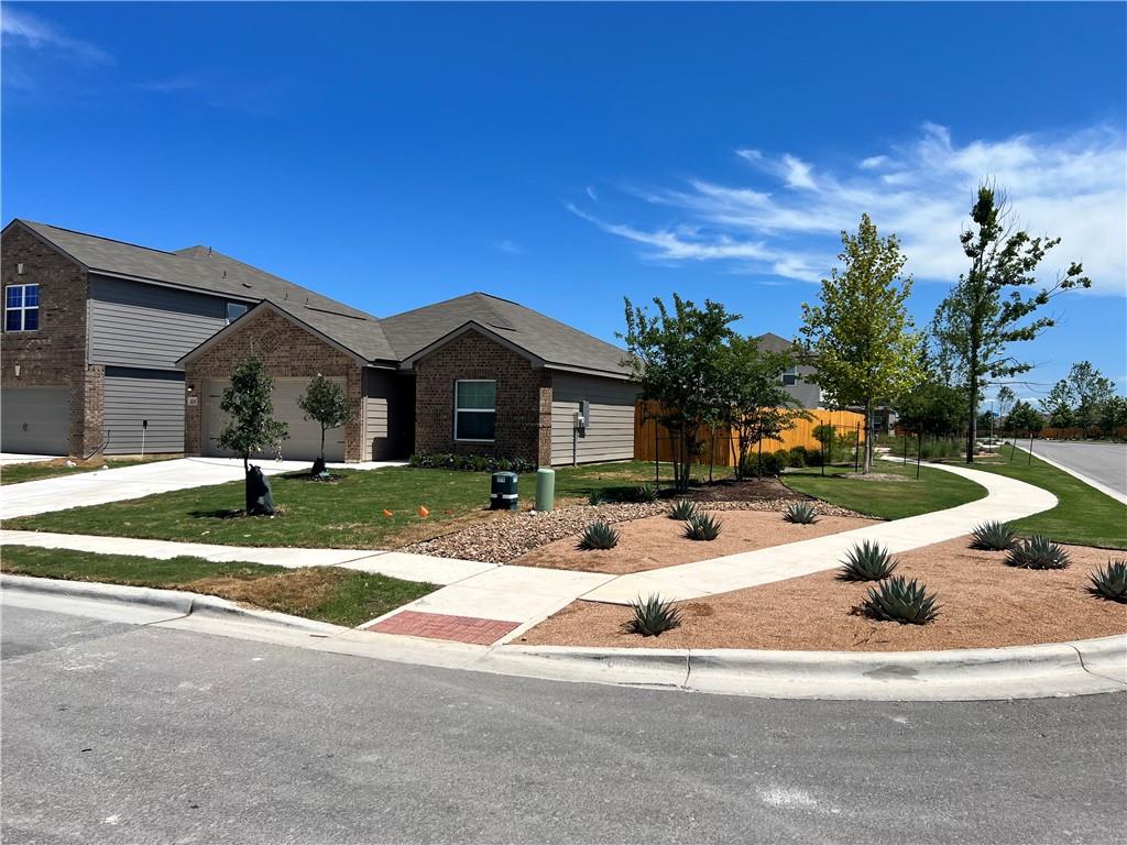 Single story home with concrete driveway, brick siding, a front yard, and an attached garage