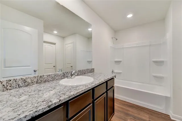 a bathroom with a granite countertop sink mirror and bathtub
