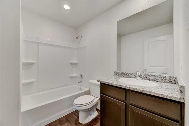 a bathroom with a granite countertop sink toilet a mirror and bathtub