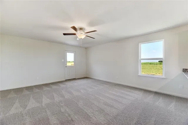 an empty room with windows and ceiling fan