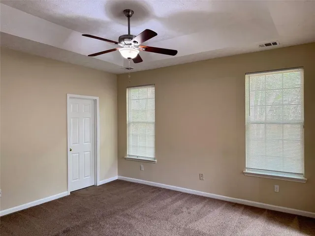 an empty room with windows and fan