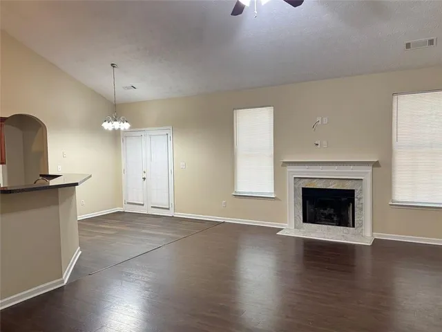 an empty room with wooden floor fireplace and windows