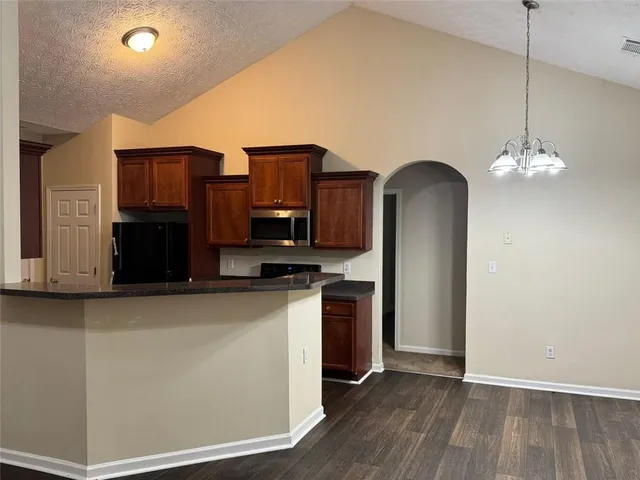 a view of kitchen with stainless steel appliances granite countertop cabinets and wooden floor