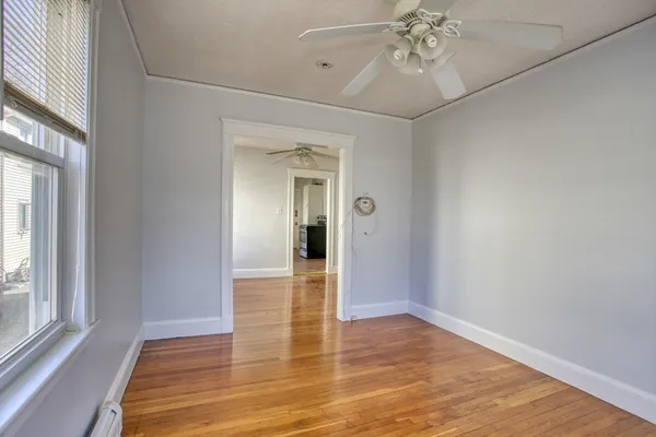 a view of an empty room with wooden floor and a window