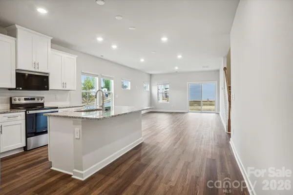 a kitchen with granite countertop a stove top oven a sink and a microwave