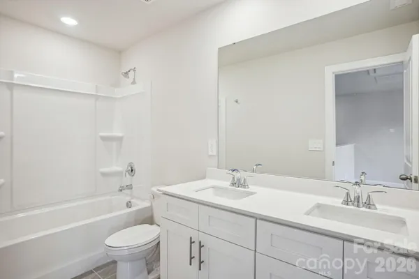 a bathroom with a bathtub shower sink vanity mirror and toilet