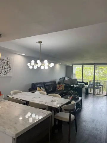 a living room with large couches chandelier and a dining table with garden view