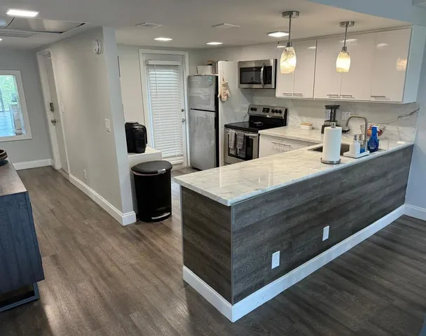 a kitchen with stainless steel appliances a refrigerator and a wooden floor