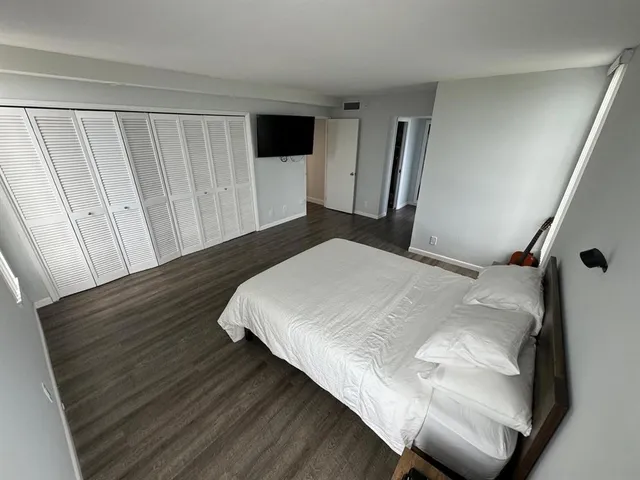 a bedroom with a bed and a flat tv screen on dresser